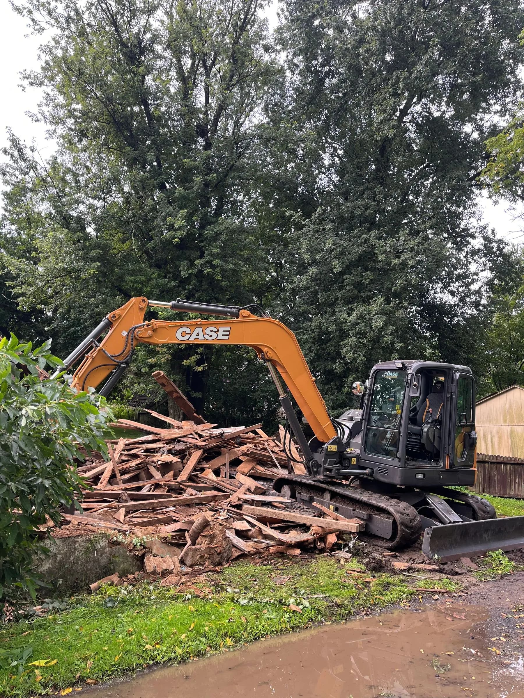 CASE excavator sorting a pile of demolished framing.