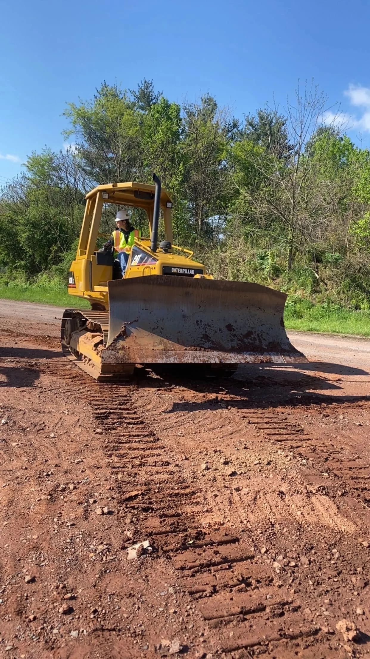 Caterpillar dozer pushing soil, operator wearing a hard hat.